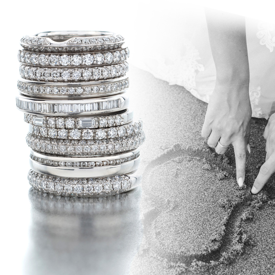 Black and white image of a stack of sterling silver wedding bands by Tom Coll Jewellery and a picture of a couple drawing a love heart in the sand